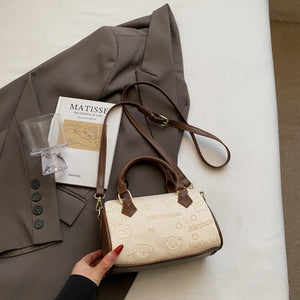 Mini crossbody bag in beige with cartoon bear and bunny pattern and brown trim.