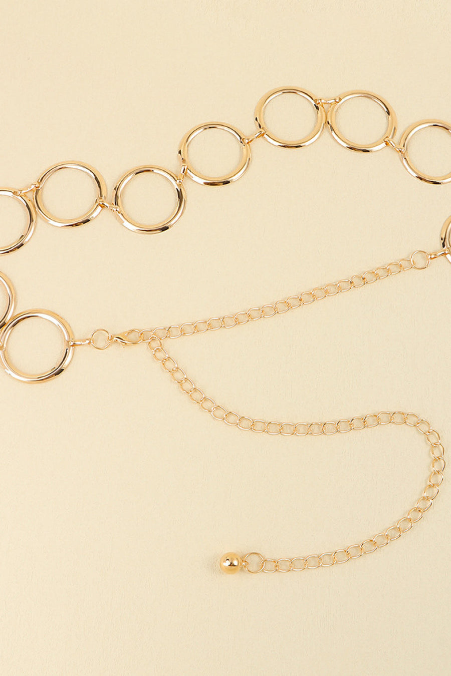Gold geometric circle waist chain with delicate link chain and ball accent.
