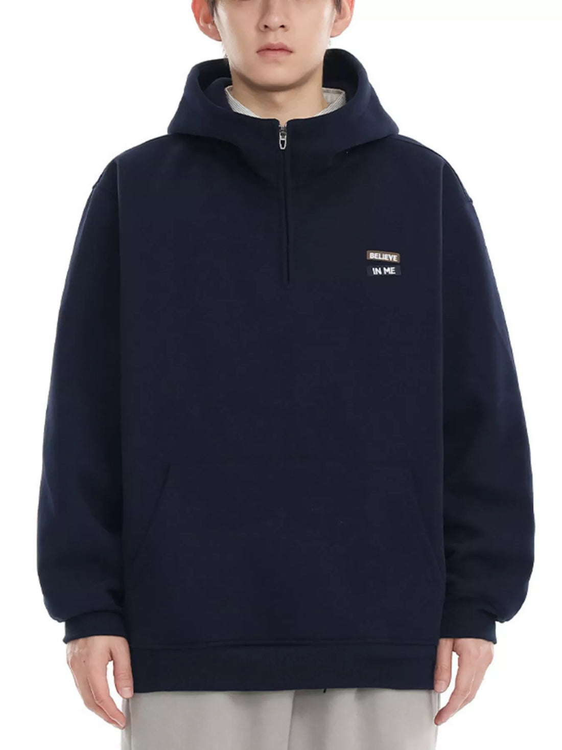Navy blue quarter-zip hoodie with a small embroidered patch that says "BELIEVE IN ME".