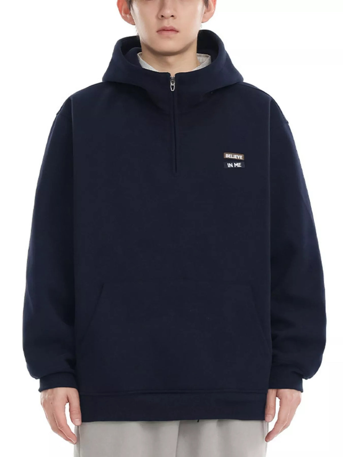 Navy blue quarter-zip hoodie with a small embroidered patch that says "BELIEVE IN ME".