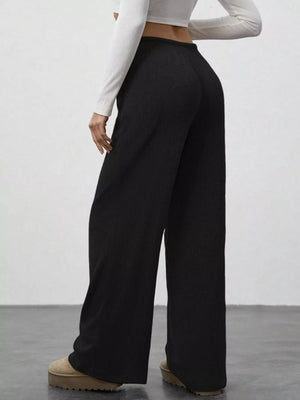 Black ribbed wide-leg pants with drawstring waist, styled with a white long-sleeve top.