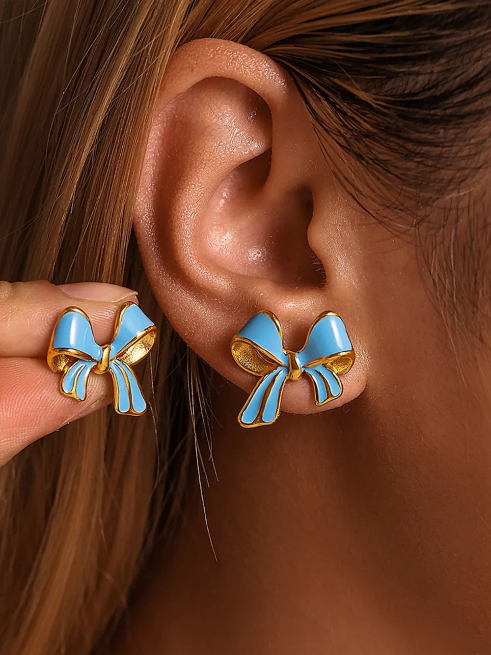 Sky blue enamel bow stud earrings with gold detailing.