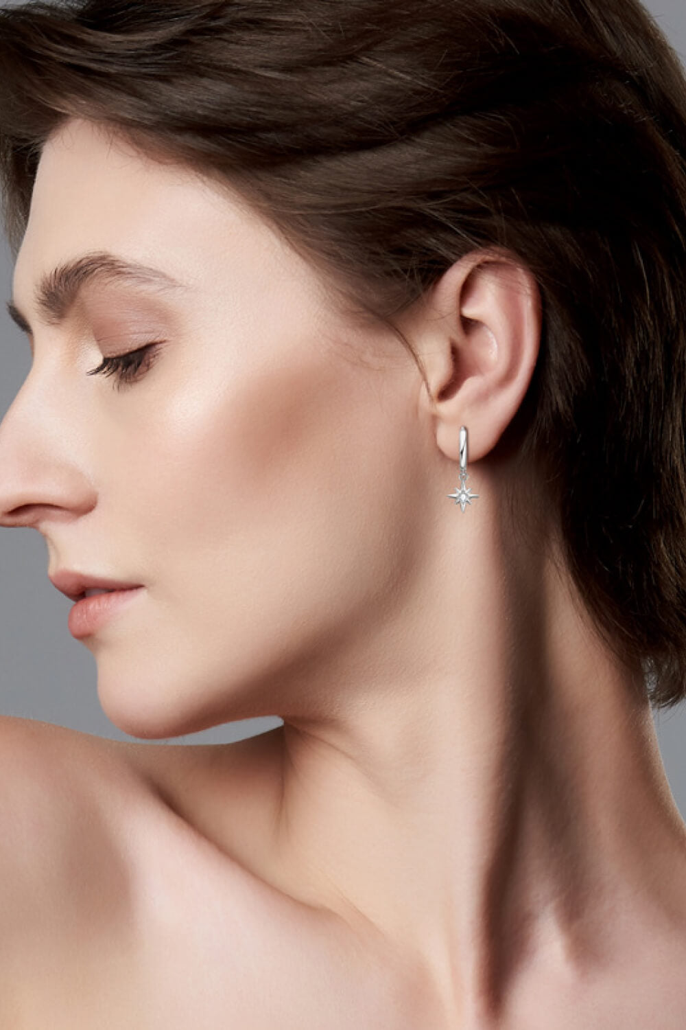 Silver hoop earrings with a dangling celestial compass charm.