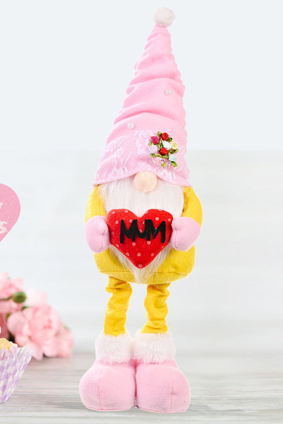 Yellow and pink gnome holding a red heart with MUM text, decorative garden ornament.