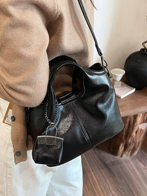Chic black PU leather crossbody bag with a mini bag charm and chain detail.