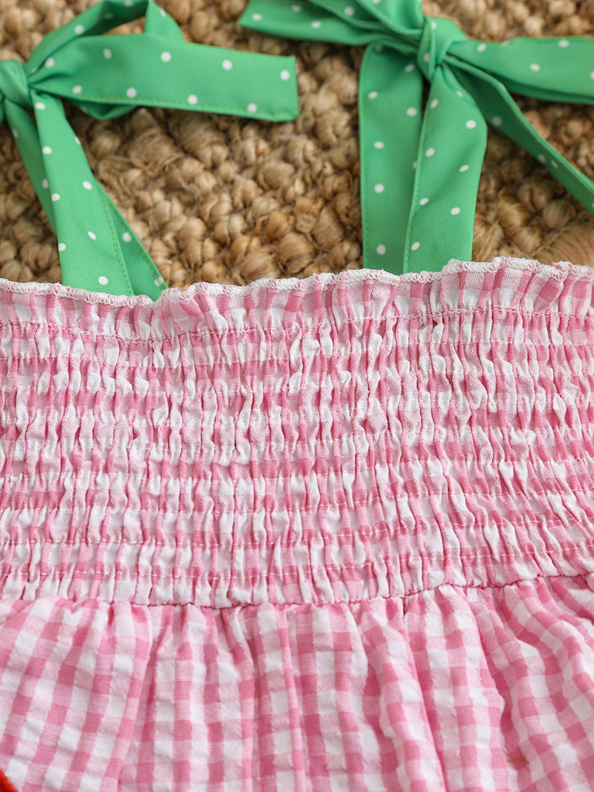 Smocked pink gingham baby dress with green polka dot tie straps.