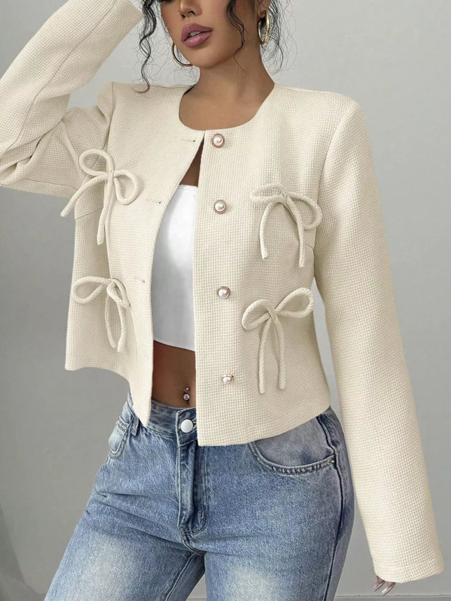Cream textured jacket with bow details and pearl buttons, round neck, long sleeves.