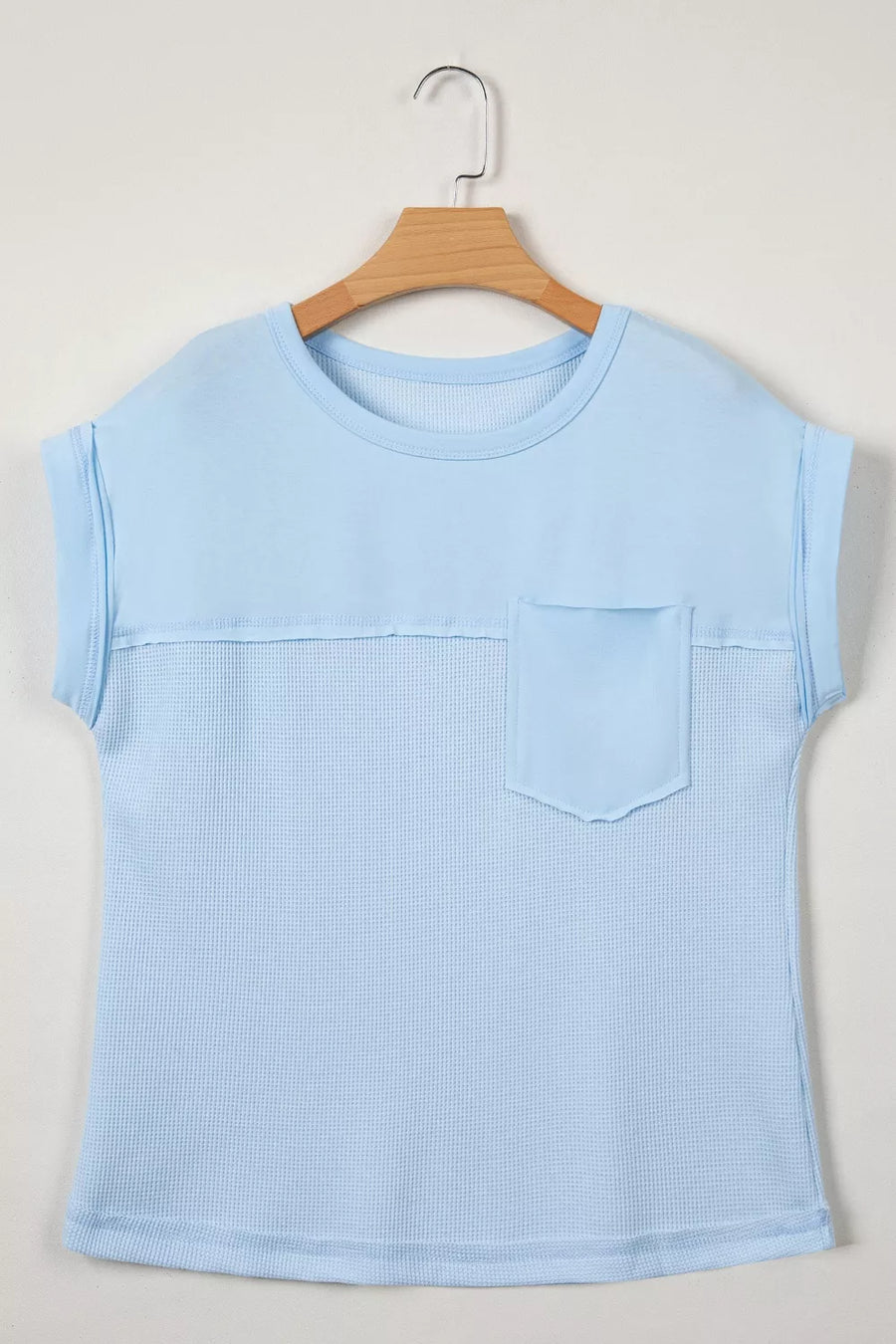 Light blue waffle knit t-shirt with short sleeves, crew neck, chest pocket, and curved hem.