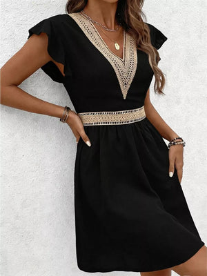 Black mini dress with chevron lace trim at V-neck and defined waist, flutter sleeves.