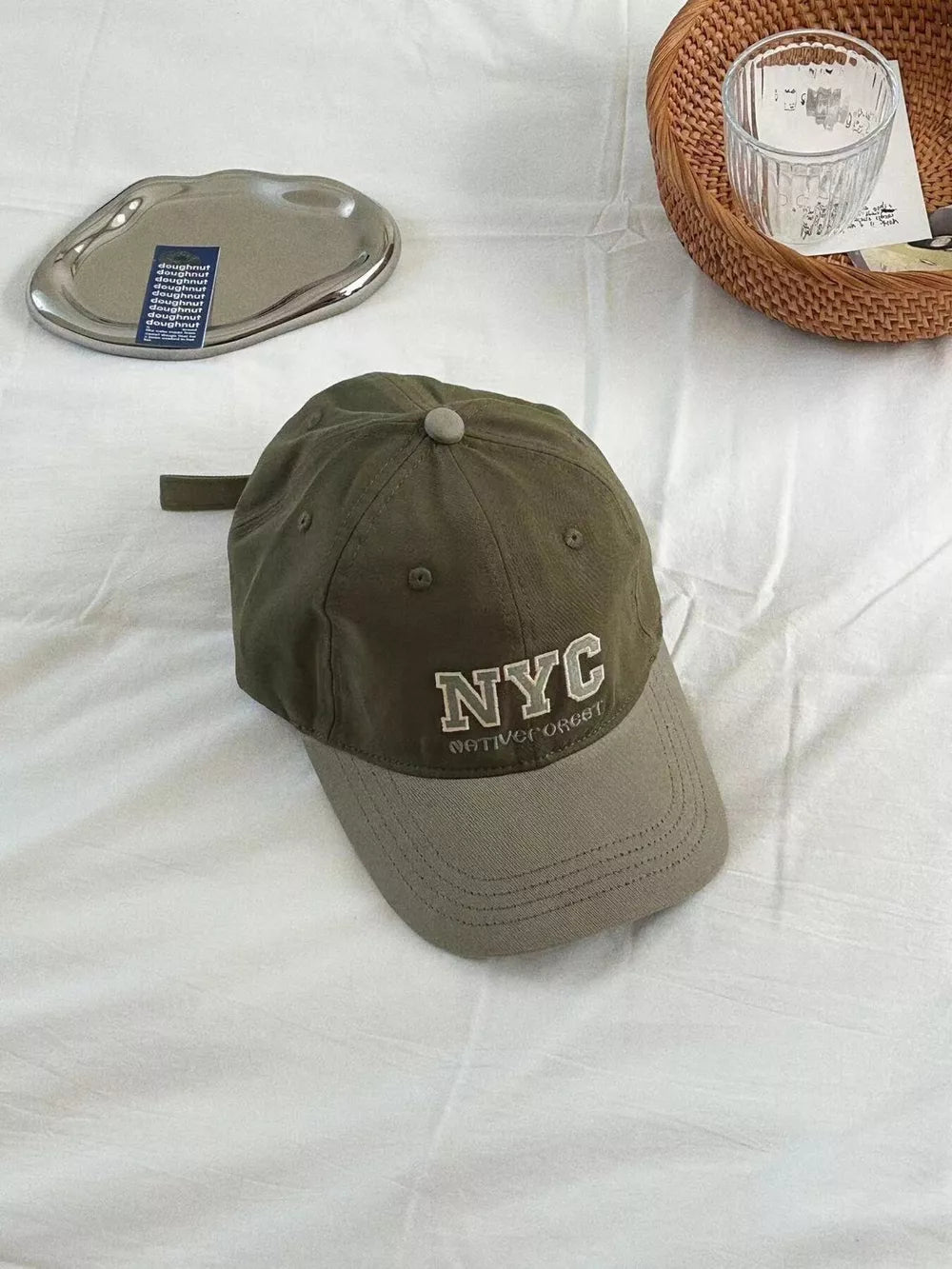 Military green cotton baseball cap with embroidered NYC logo and adjustable strap.