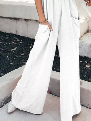 White smocked pocketed wide leg romper with pockets and a relaxed fit.