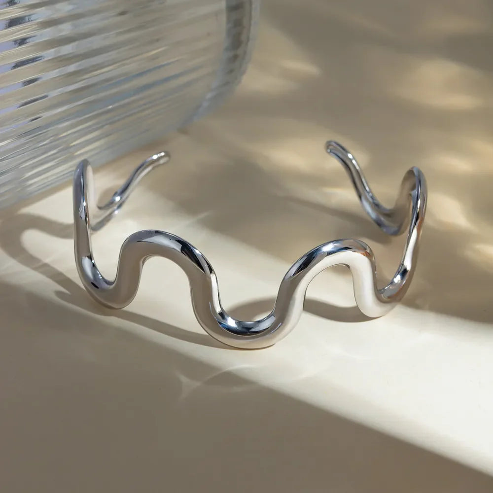 Sculptural silver cuff bracelet with a wavy, fluid design.