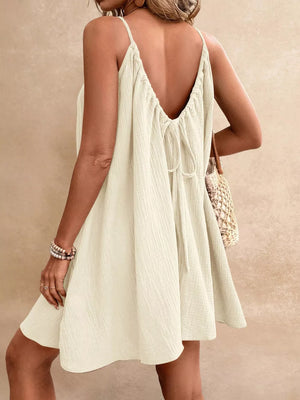 Spaghetti strap gauze dress in cream with a tie-back detail and A-line skirt.