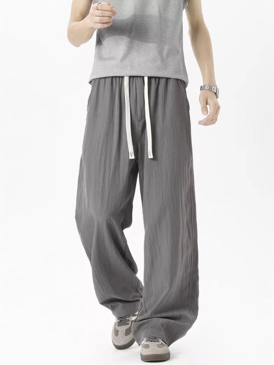 Men's grey lightweight track pants with drawstring waist and wide leg