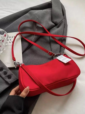 Red nylon mini crossbody bag with adjustable strap and silver hardware.