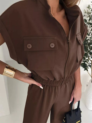 Brown short sleeve jumpsuit with zip front, chest pockets, elastic waist, and wide leg.