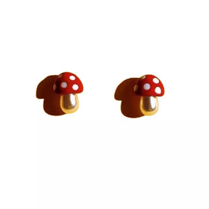 Red mushroom stud earrings with white polka dots and gold stems.