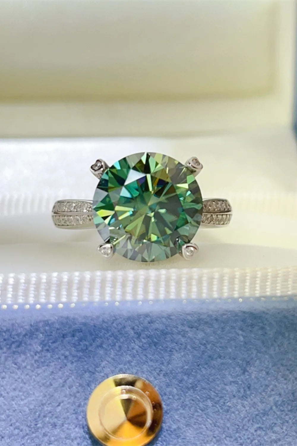 Verdant moissanite solitaire ring with a silver band and diamond accents.