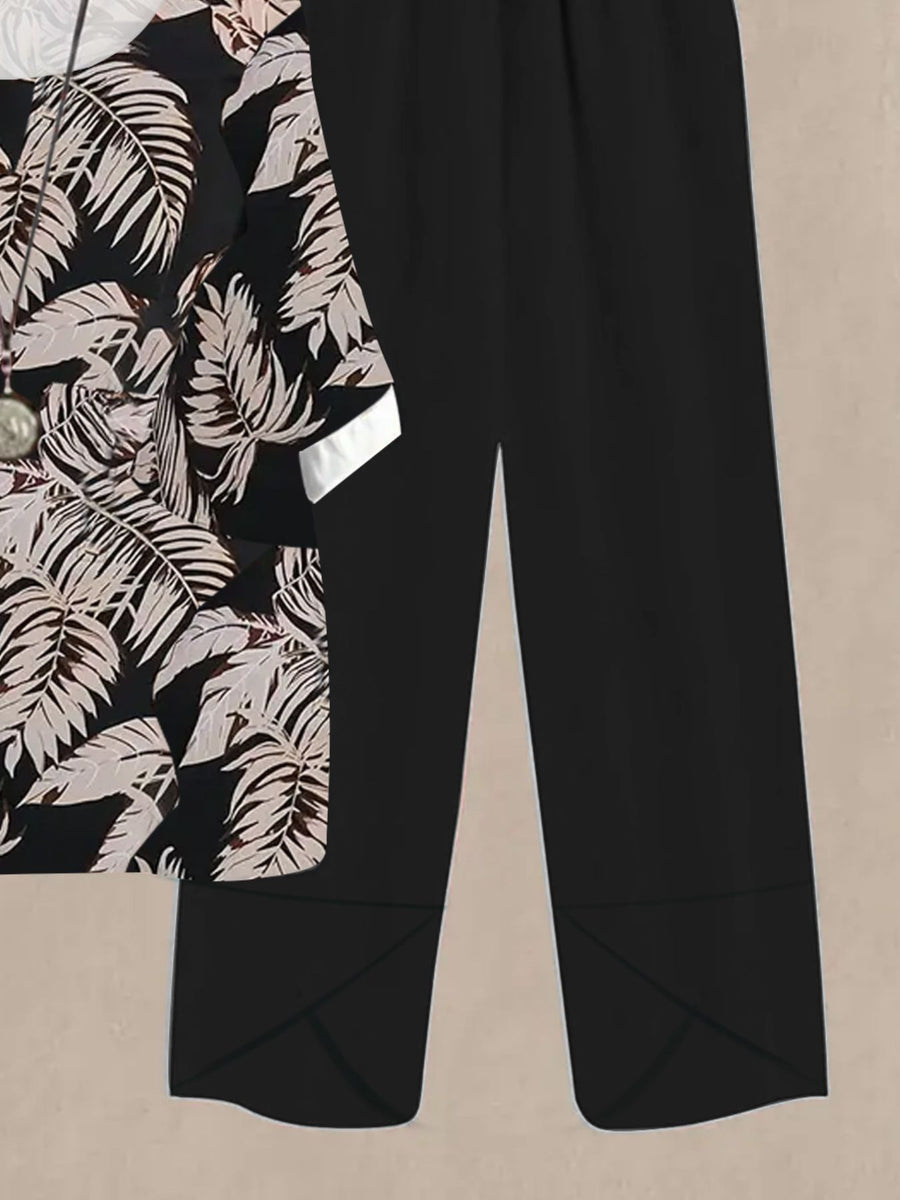 Black floral print half sleeve top with white cuffs paired with black wide leg pants.