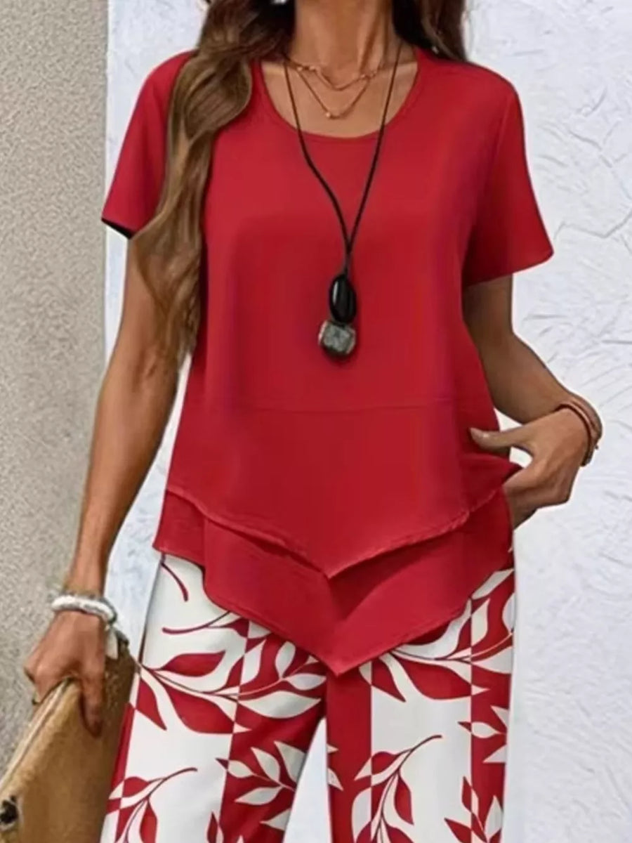 Red layered short sleeve top with a tiered hem, paired with white and red leaf print pants.