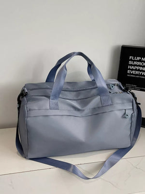 Duffel bag in light blue nylon with multiple zippered pockets and adjustable strap.