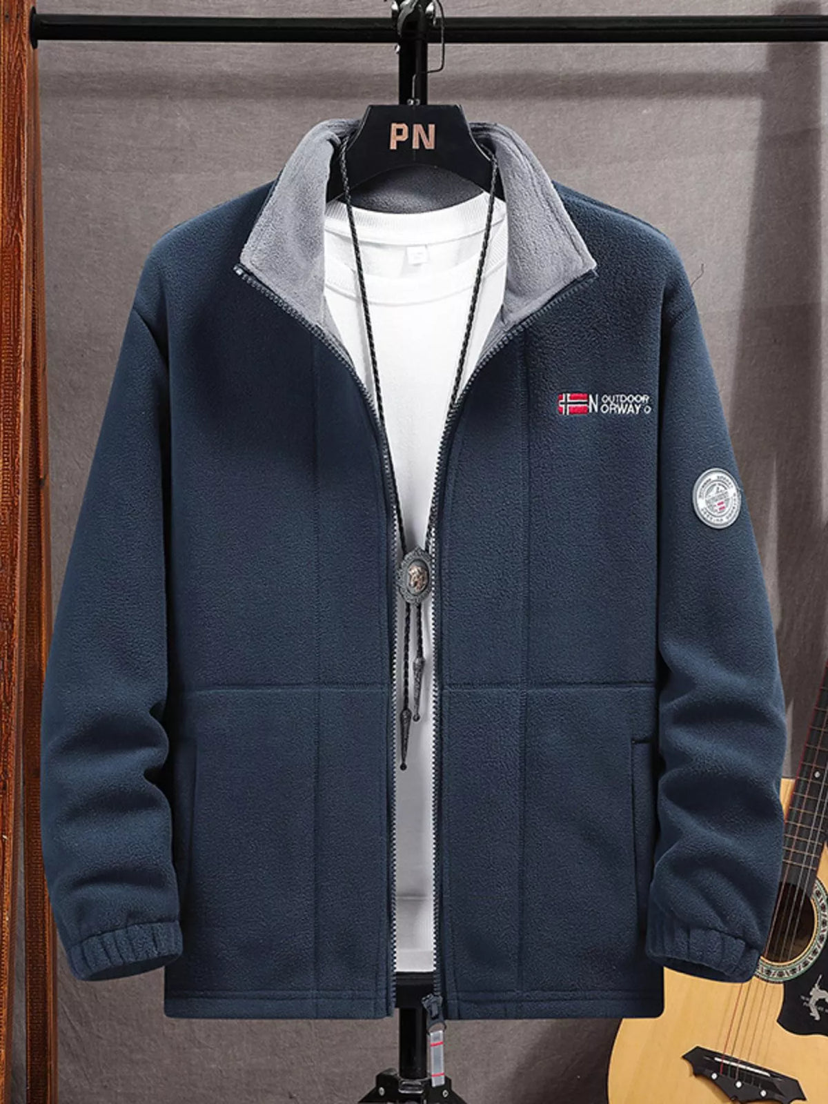 Men's dark blue fleece zip-up jacket with embroidered logo and grey collar.