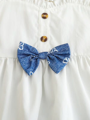 White cotton cami with sweetheart neckline, button front, and blue patterned bow detail.