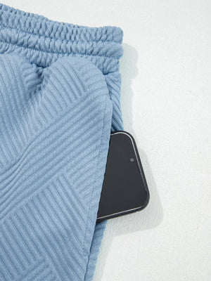 Light blue textured drawstring shorts with a phone in the pocket.