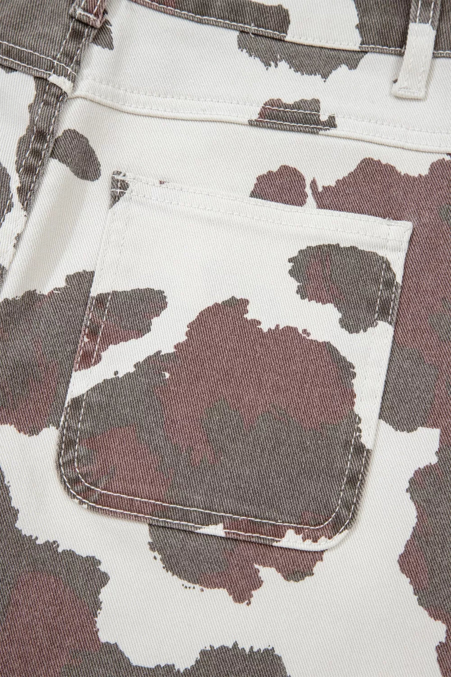 Cow print utility jeans with a visible cargo pocket detail.