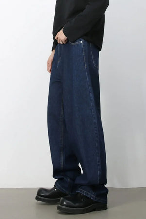 Faded baggy denim jeans in dark blue, styled with a black top and chunky shoes.
