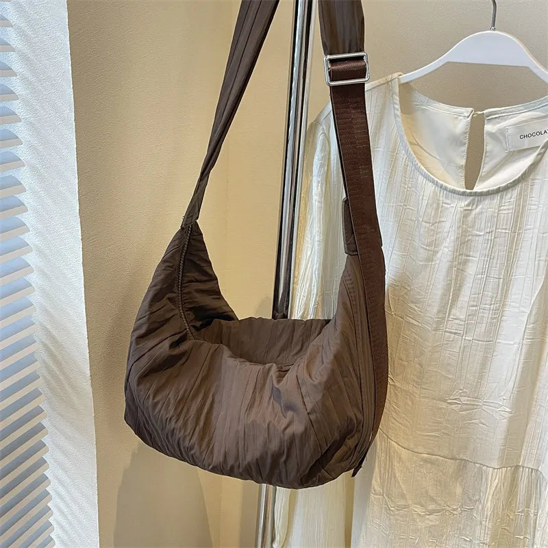 Quilted crescent shoulder bag in coffee brown with adjustable strap.