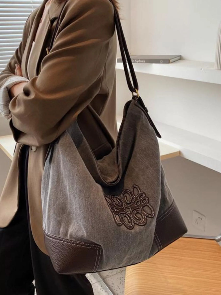 Medium canvas tote bag in grey with brown leather trim and embroidered detail.