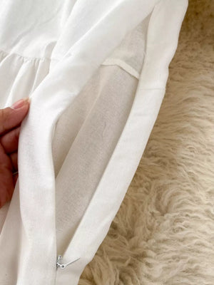 White embroidered maxi dress with balloon sleeves, showing zipper detail.