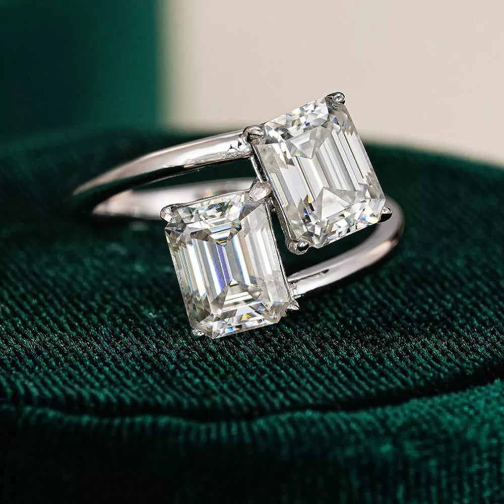 Emerald-cut moissanite bypass ring in silver with two radiant stones.