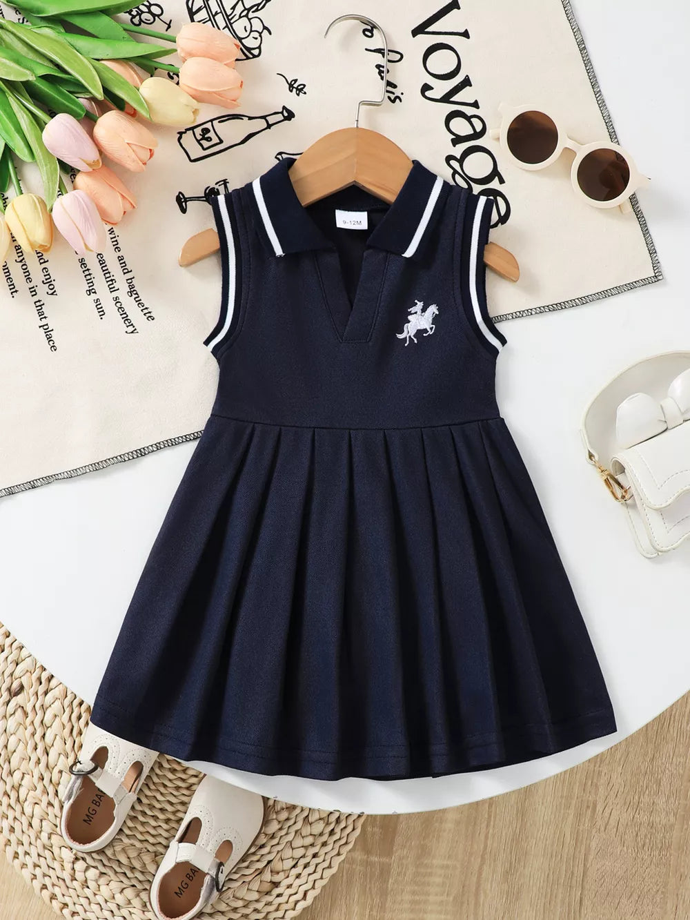 Navy sleeveless baby dress with white trim collar and equestrian embroidery, pleated skirt.