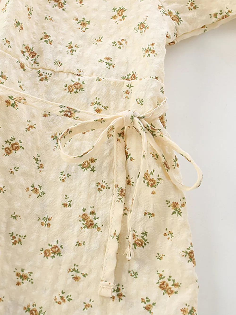 Cream floral puff sleeve toddler dress with a tie waist and button detail.