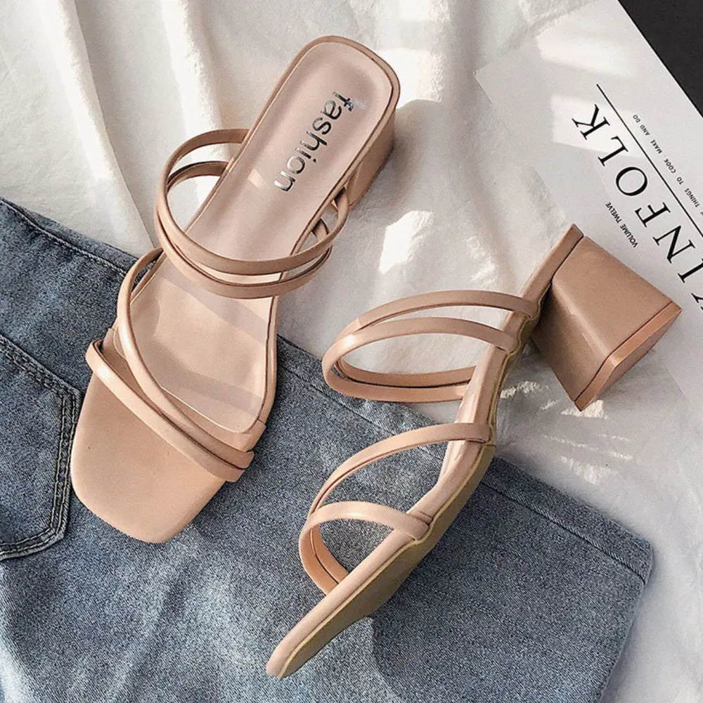 Strappy minimalist block heel mules in beige with a square toe and open back.