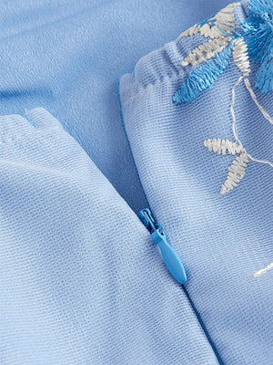 Blue mini dress with floral embroidery and tie shoulder detail, featuring a side zipper.