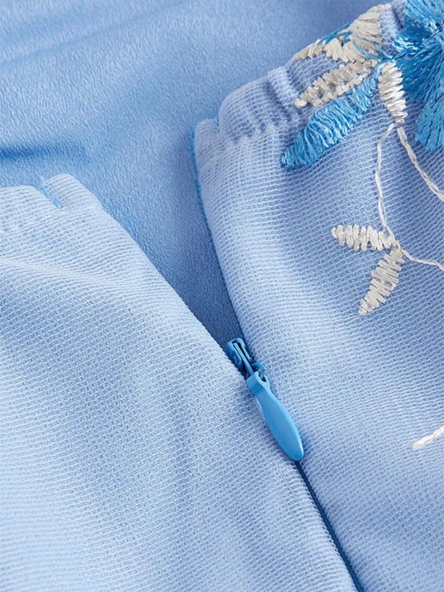Blue mini dress with floral embroidery and tie shoulder detail, featuring a side zipper.