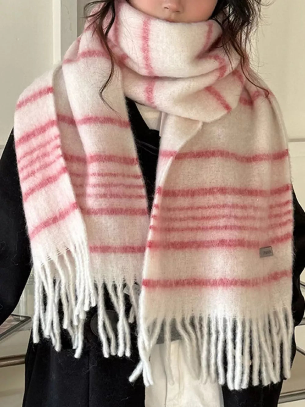 Chic pink and white striped scarf with fringe hem and cozy texture.