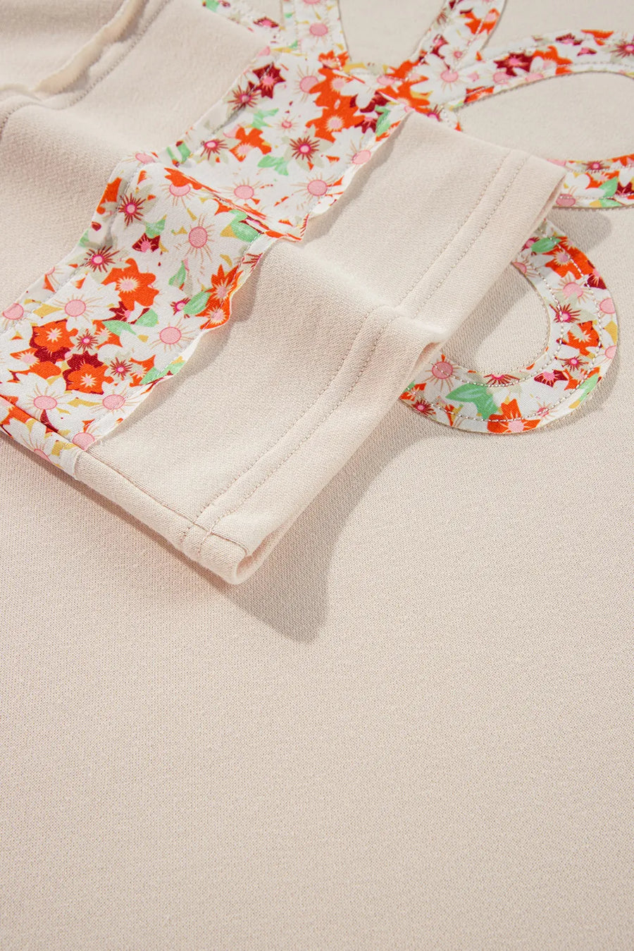 Ivory sweatshirt with floral appliqué raglan sleeves and crew neck detail.