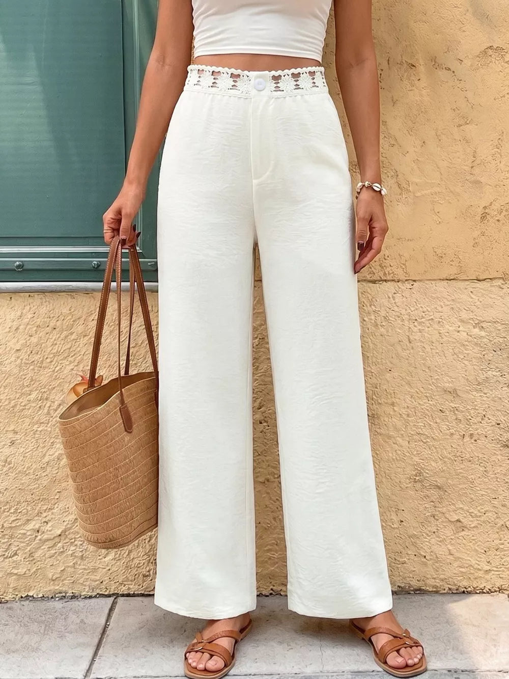 White wide-leg pants with crochet waistband detail and button closure.