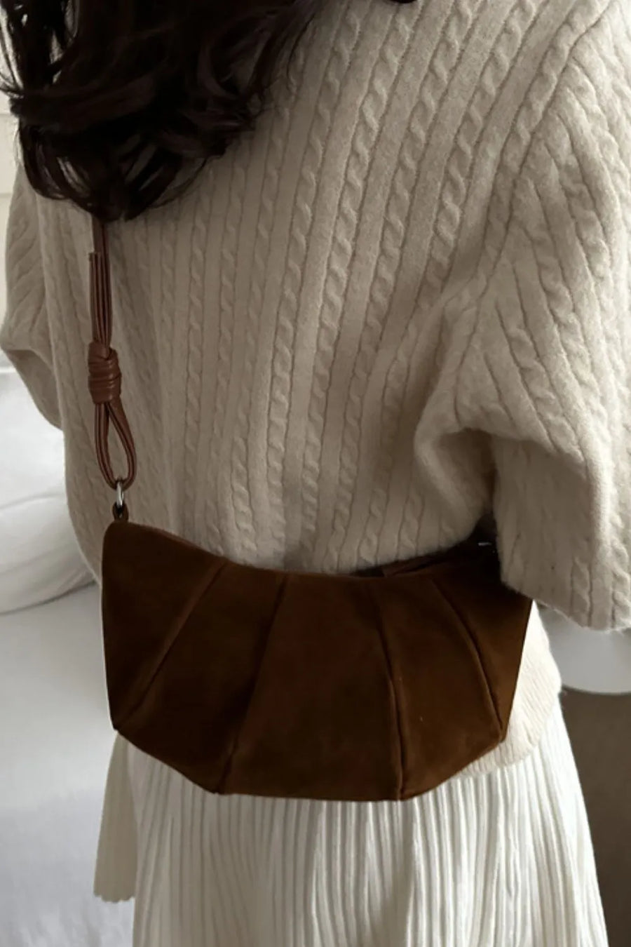 Pleated suede crescent shoulder bag in brown with a knotted strap detail.
