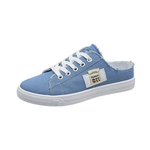 Light blue denim mule sneakers with raw edges and white laces.