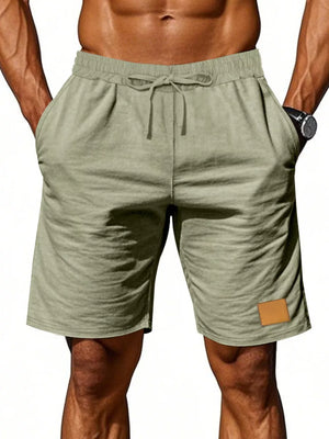 Light green chino shorts with drawstring waist and leather patch detail