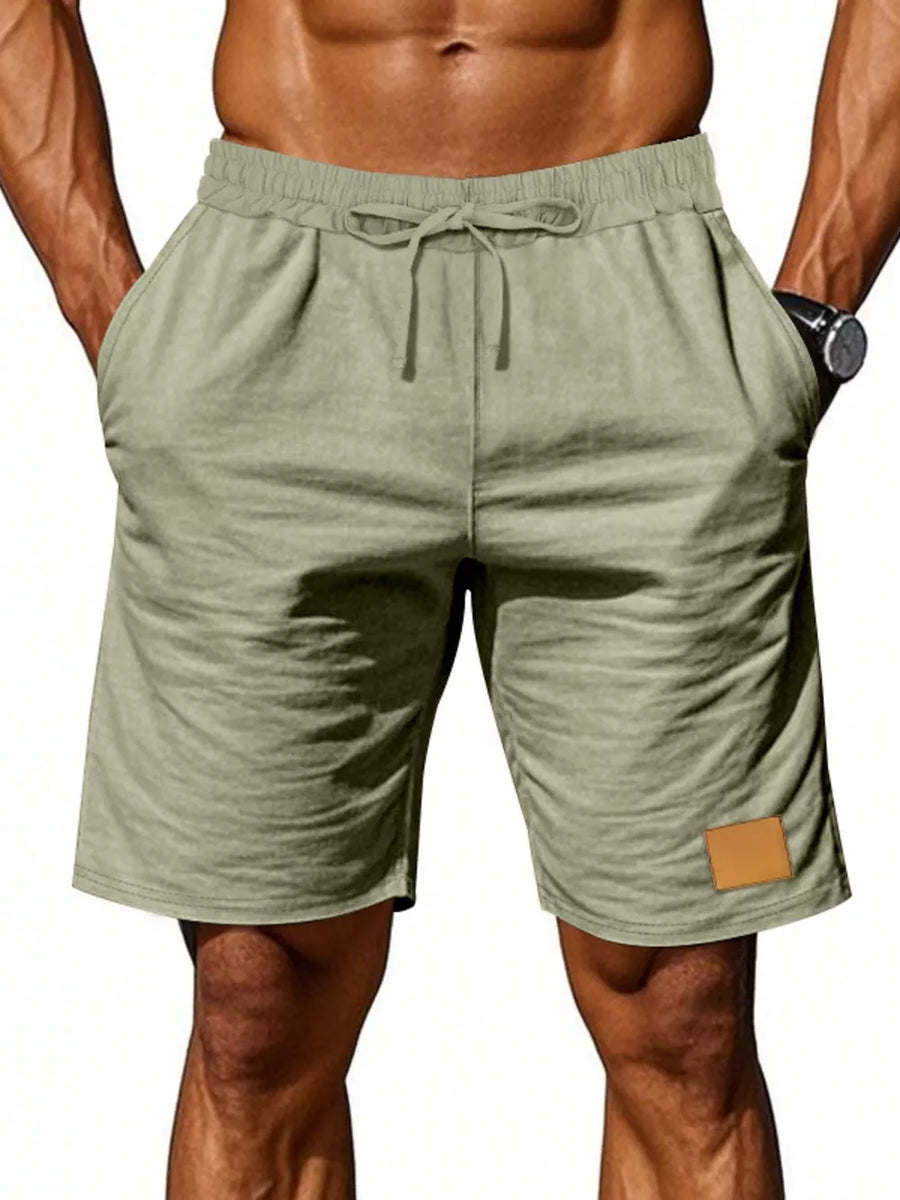 Light green chino shorts with drawstring waist and leather patch detail