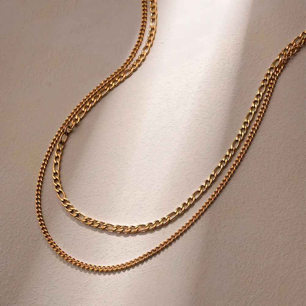Gold dual-strand curb chain necklace with Figaro and fine link styles.