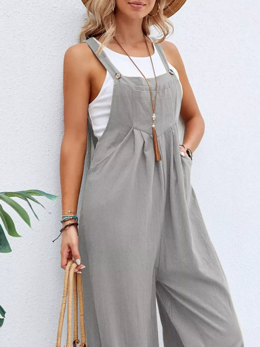 Light gray wide-leg romper with pockets, button straps, and a white tank top.