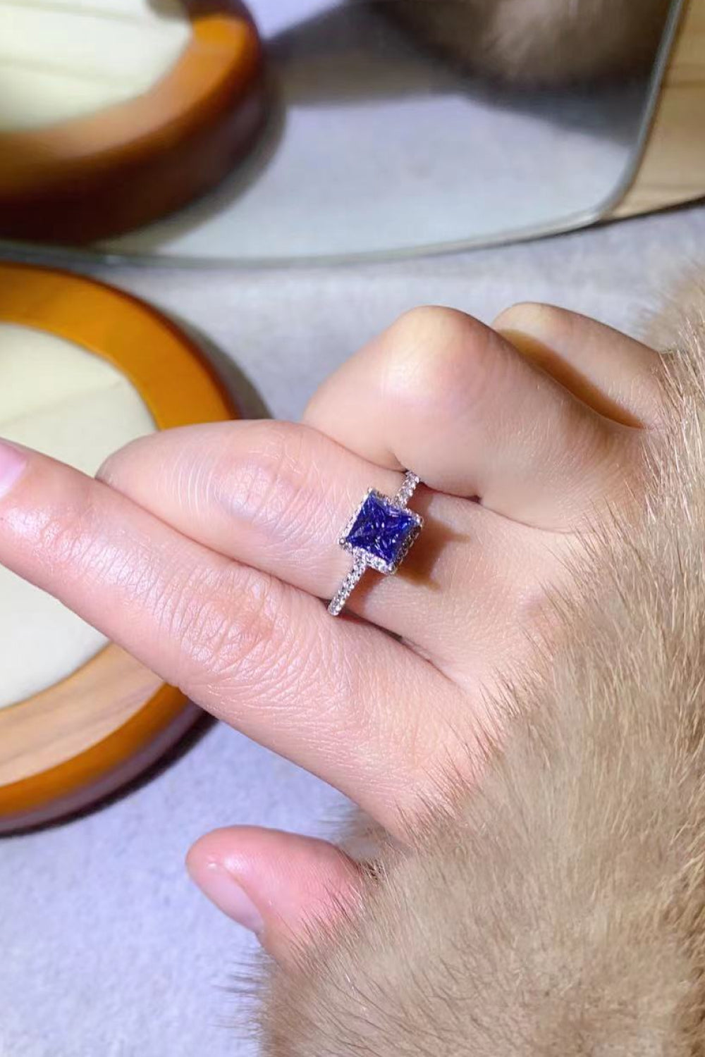 Blue square halo ring with pave band on finger