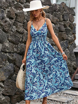 Maxi dress with blue paisley print, V-neck, spaghetti straps, smocked waist, and flowing skirt.